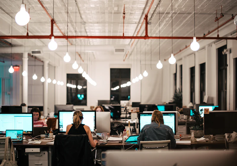 Oficina iluminada de noche con equipos de trabajo encendidos